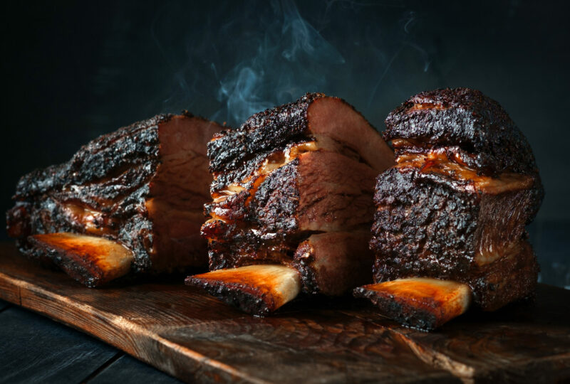 A large steaming fragrant piece of baked beef brisket on the ribs with a dark crust. Classic Texas barbecue